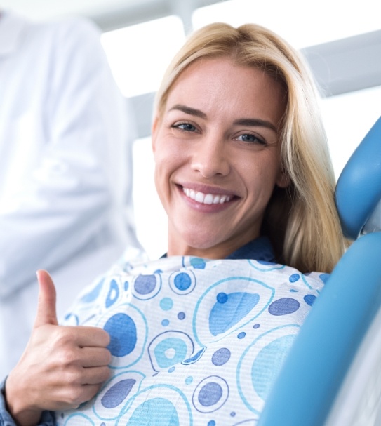 Woman in dental chair giving a thumbs up