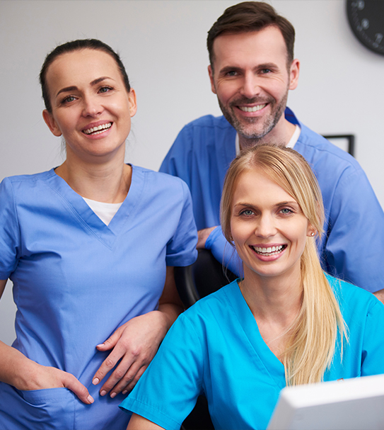 Three friendly dental team members at reception desk