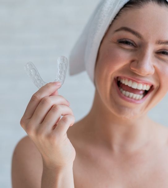 Smiling woman holding nightguard for bruxism