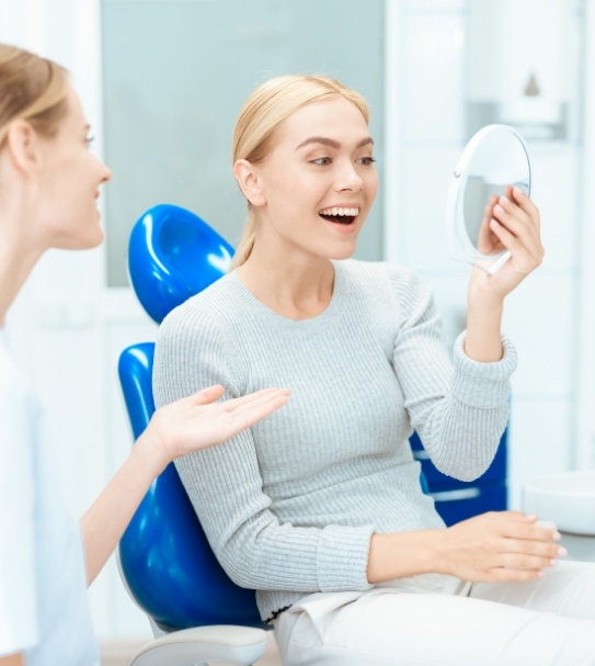 Woman looking at flawless smile after cosmetic dentistry