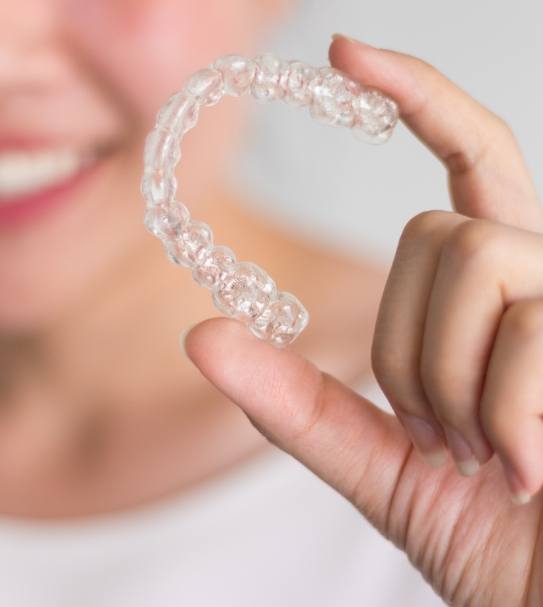 Hand holding an Invisalign tray