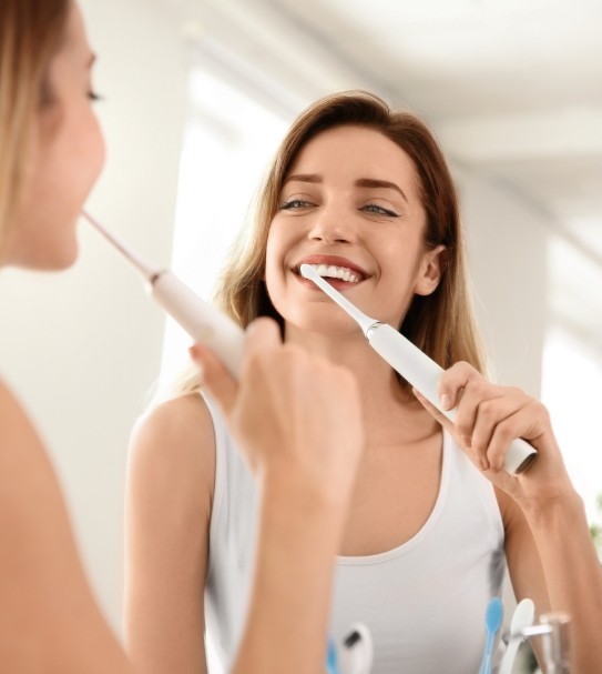 Woman brushing teeth to prevent dental emergencies