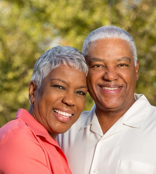 Older couple with dental implants smiling together