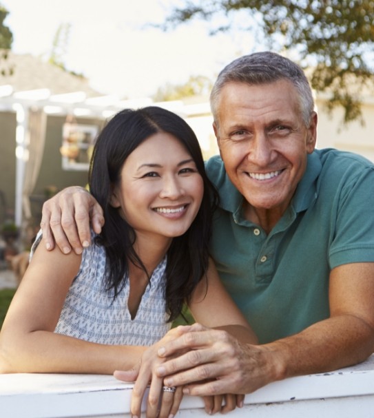 Smiling man and woman enjoying the benefits of dental implants
