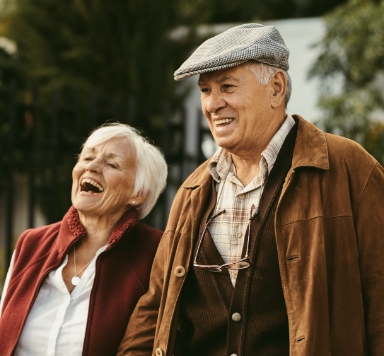 Older man and woman smiling after replacing missing teeth