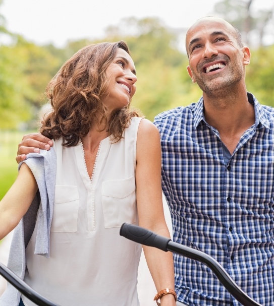 Man and woman smiling after replacing missing teeth