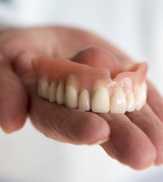 Hand holding a full denture